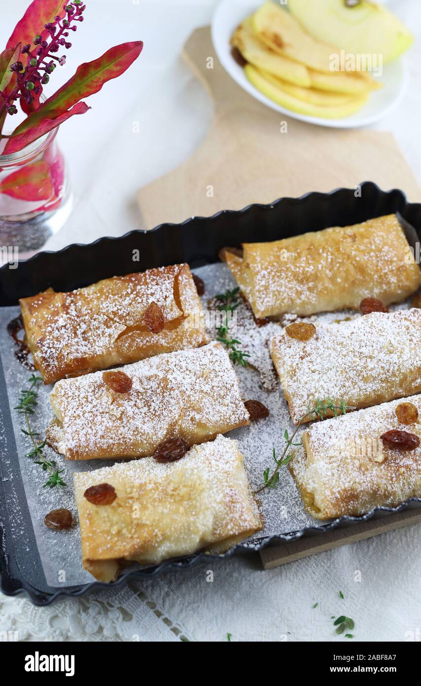 Top view of homemade phyllo dough rolls with apples and orange marmalade. White background with sultanas. Stock Photo