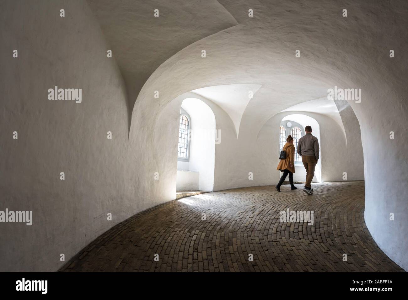 Young couple walking, view of young people ascending the equestrian staircase or helical ramp inside the Rundetaarn in central Copenhagen, Denmark. Stock Photo