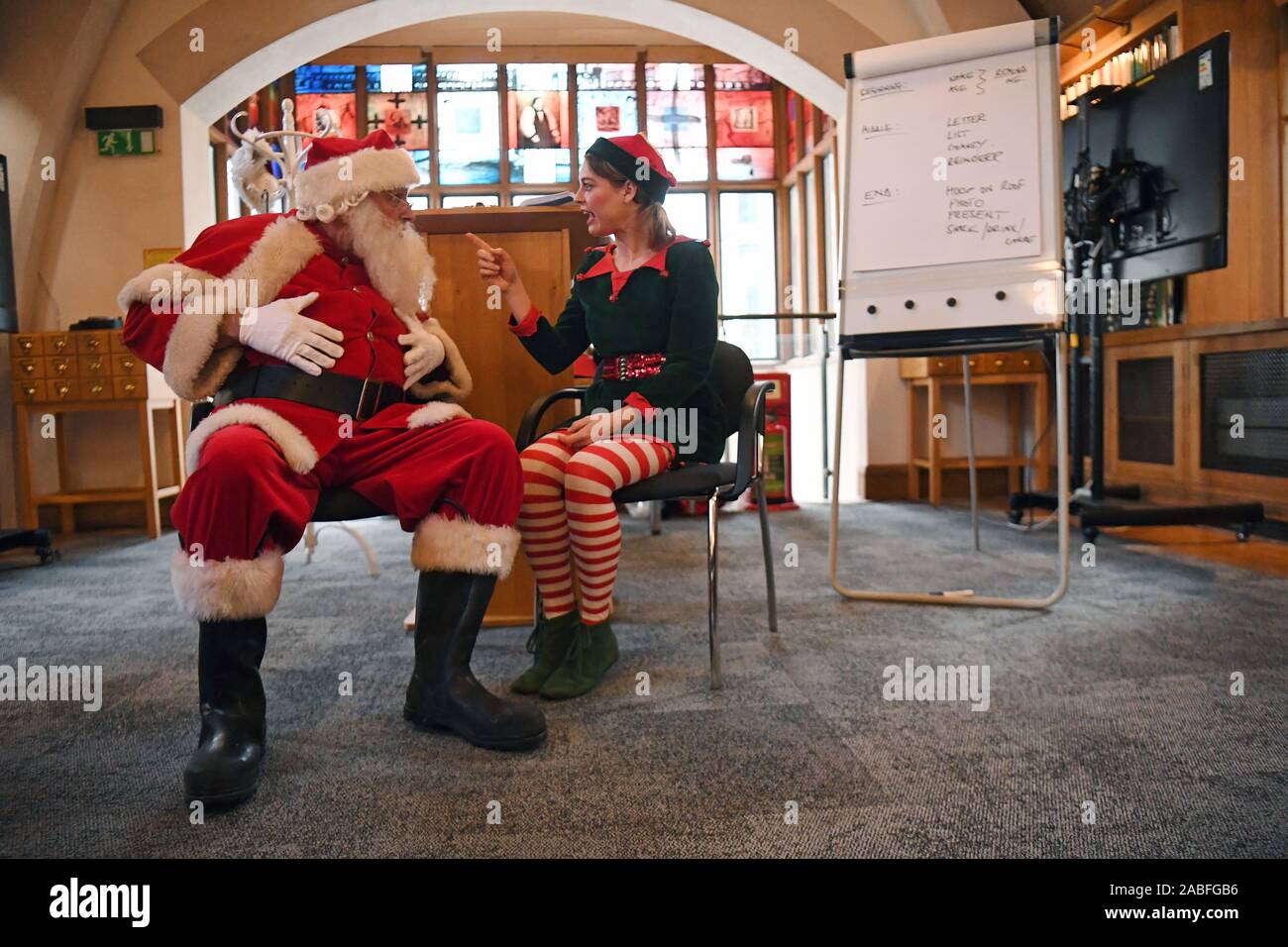 A Father Christmas performer talks to an Elf, pretending to be a child, in a classroom during the 23rd annual Santa School at Southwark Cathedral in London. PA Photo. Picture date: Wednesday November 27, 2019. With a global shortage of Santas, the Ministry of Fun is boosting numbers by holding the school in the capital. Photo credit should read: Kirsty O'Connor/PA Wire Stock Photo