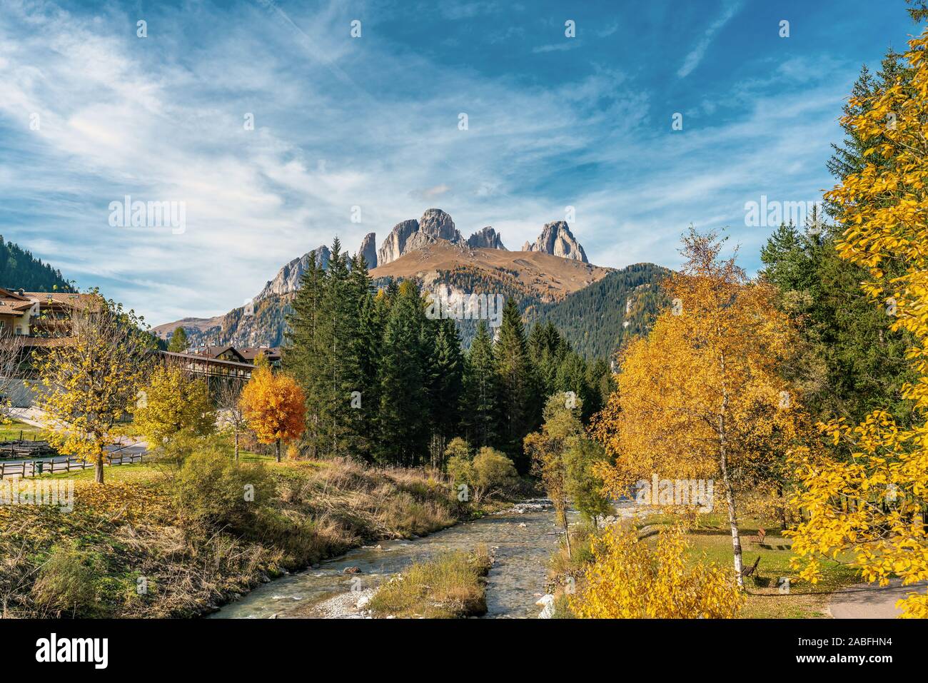 Colourful autumn picture of the Sella massif mountains and the Avisio river in the village Alba di Canazei in South Tyrol, Italy Stock Photo