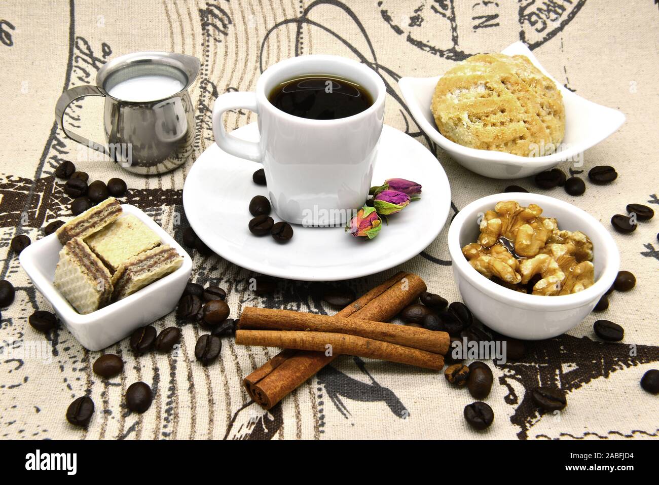 Light breakfast with coffee and desserts. Coffee, milk, waffles, cookies and nuts. Stock Photo