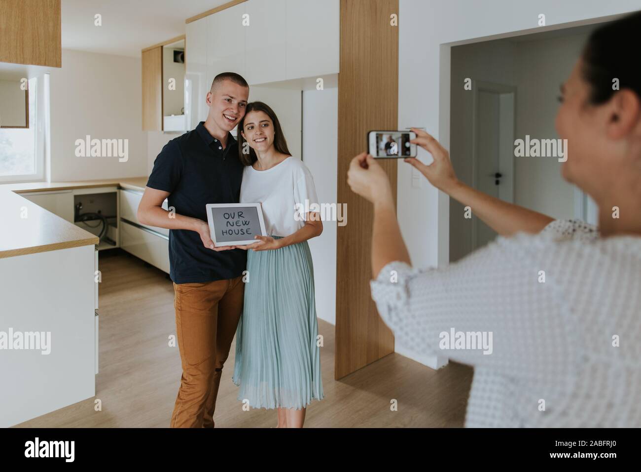 Woman taking photo of young couple in new house Stock Photo