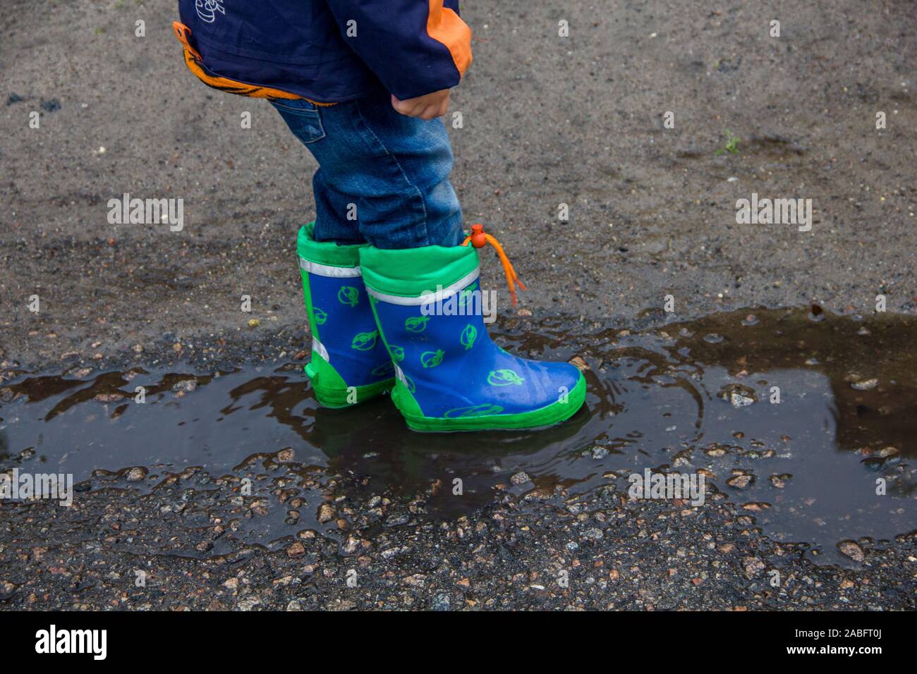 Children's feet in rubber boots in a puddle Stock Photo - Alamy