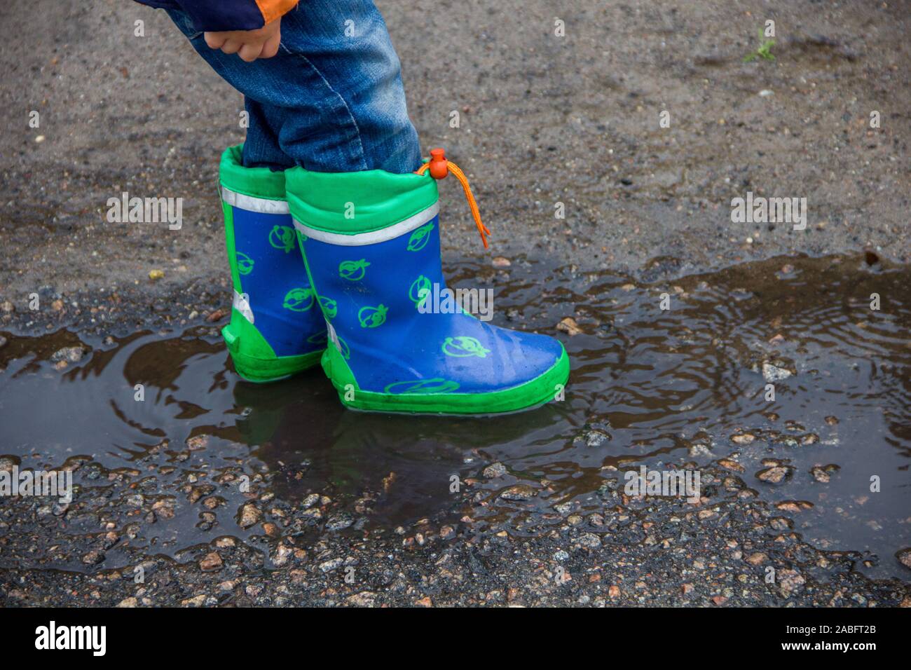 Children's feet in rubber boots in a puddle Stock Photo - Alamy