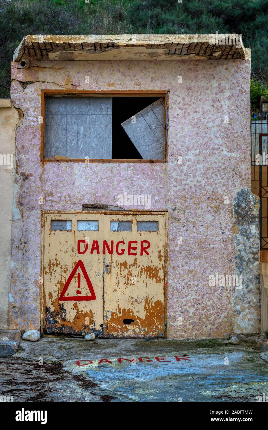 The fishing village of Dahlet Qorrot on the island of Gozo, Malta. Purpose built but now disused boathouse. Danger sign. Stock Photo