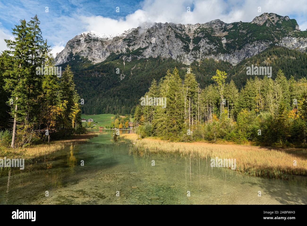 Stunning view of Hintersee with beautiful reflections of trees and houses and the Alps in background, on a sunny autumn day at Ramsau in Berchtesgaden Stock Photo