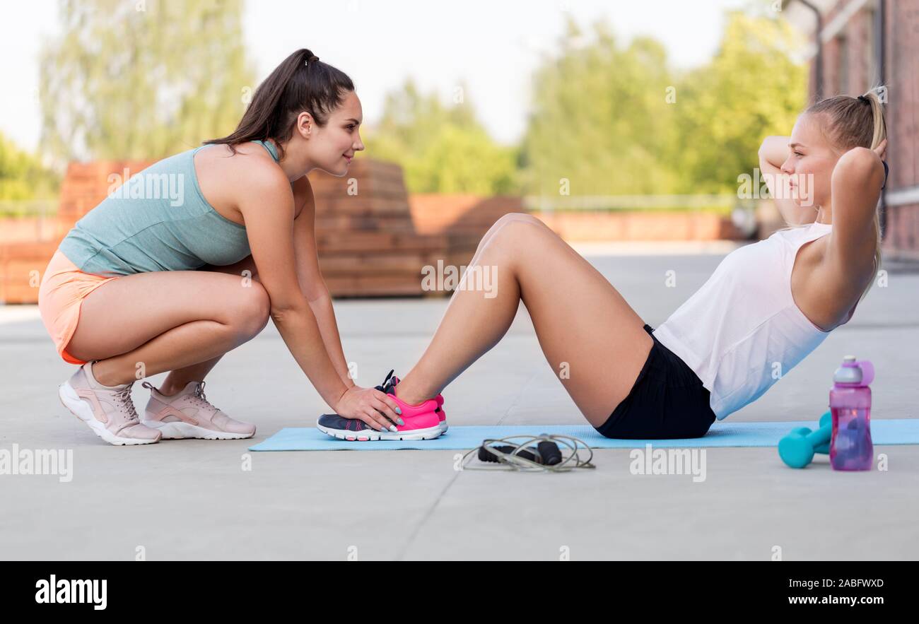 women training and doing sit-ups outdoors Stock Photo
