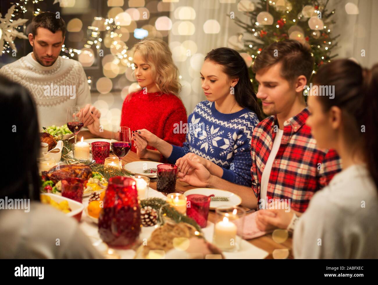 friends having home christmas dinner and praying Stock Photo