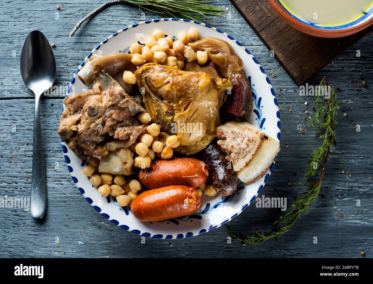 cocido madrileno, typical of Madrid, Spain, with the soup served in an earthenware bowl and the meat and vegetables used in the broth served in a tray Stock Photo