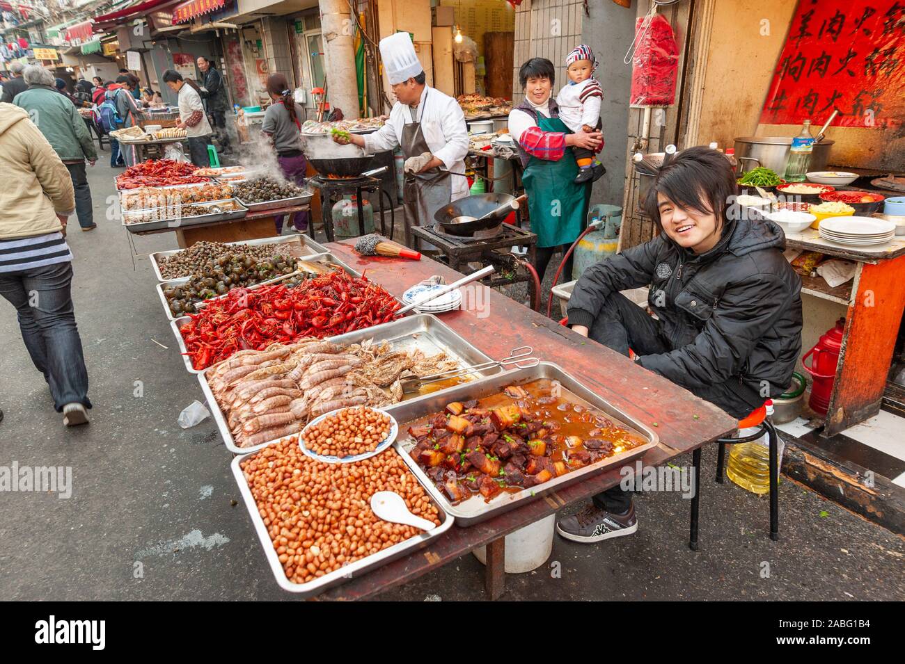 Aspirational teenager on his parents market stall selling street food in the Old City, Shanghai, China Stock Photo