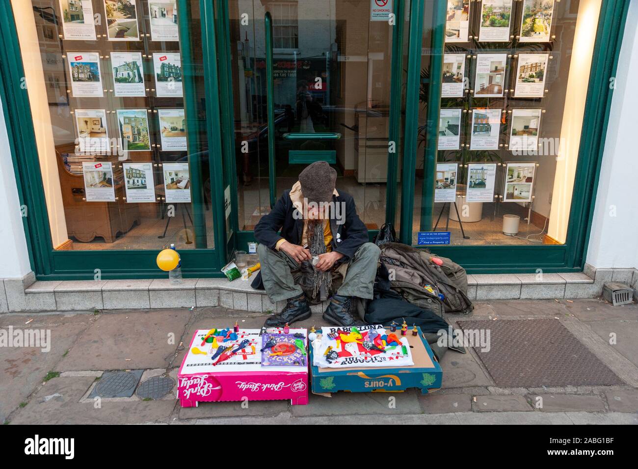 Homeless man sitting outside estate agent, Camden, London, UK Stock Photo