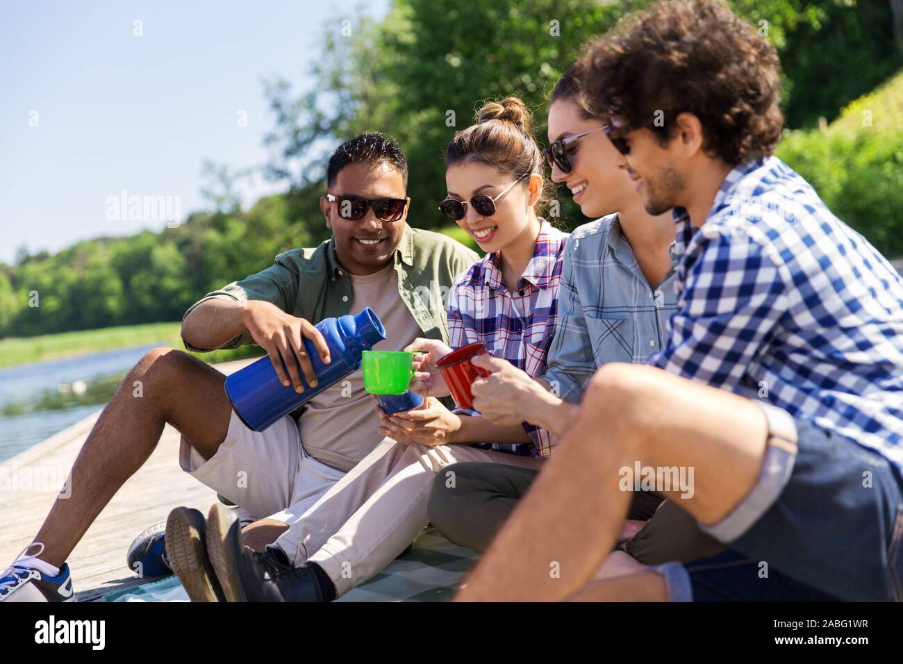 happy friends drinking tea from thermos in summer Stock Photo - Alamy