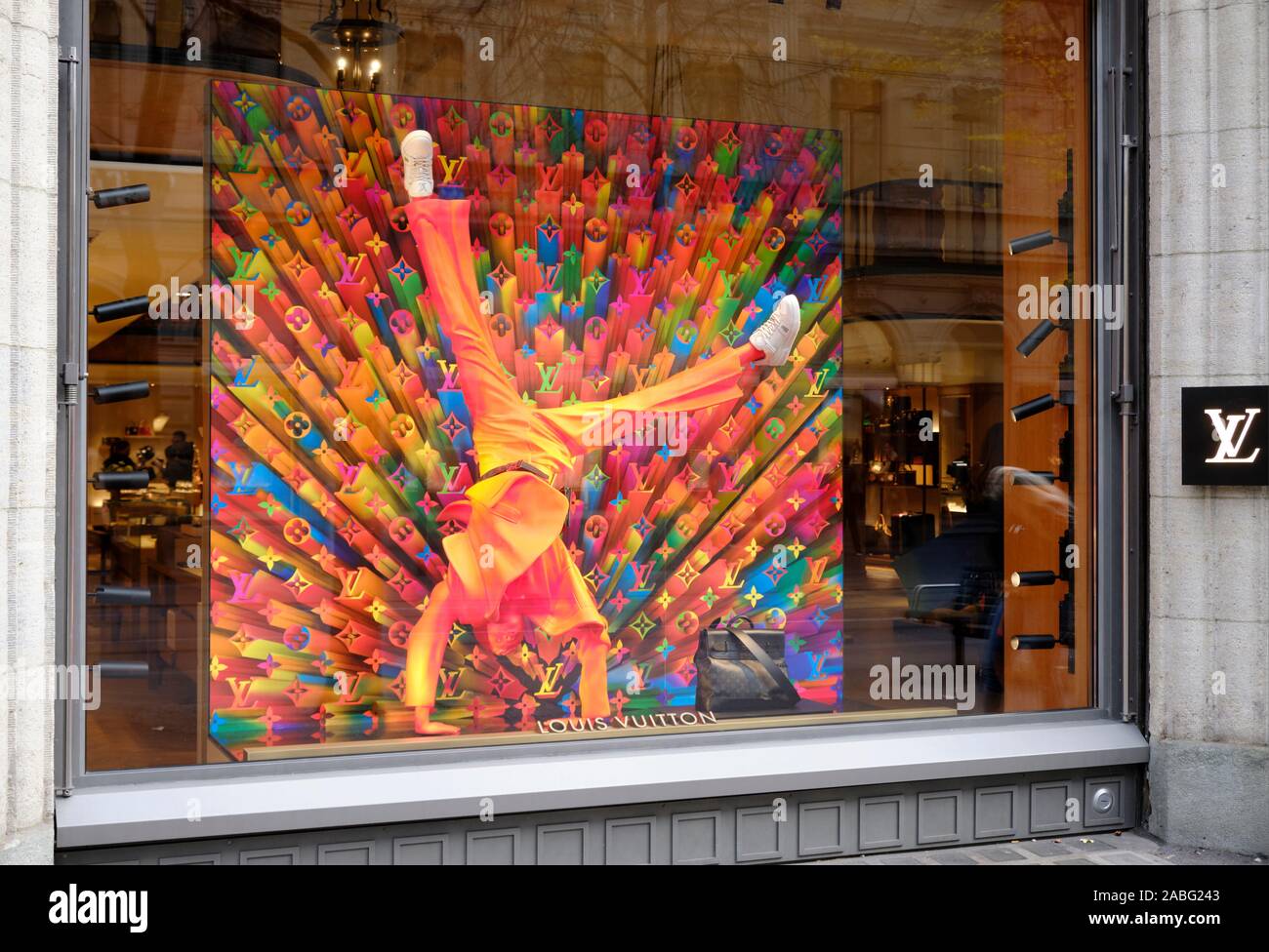 Louis Vuitton colourful window display in the Zurich Bahnhofstrasse store, with people reflection featuring a mannequin doing a handstand Stock Photo