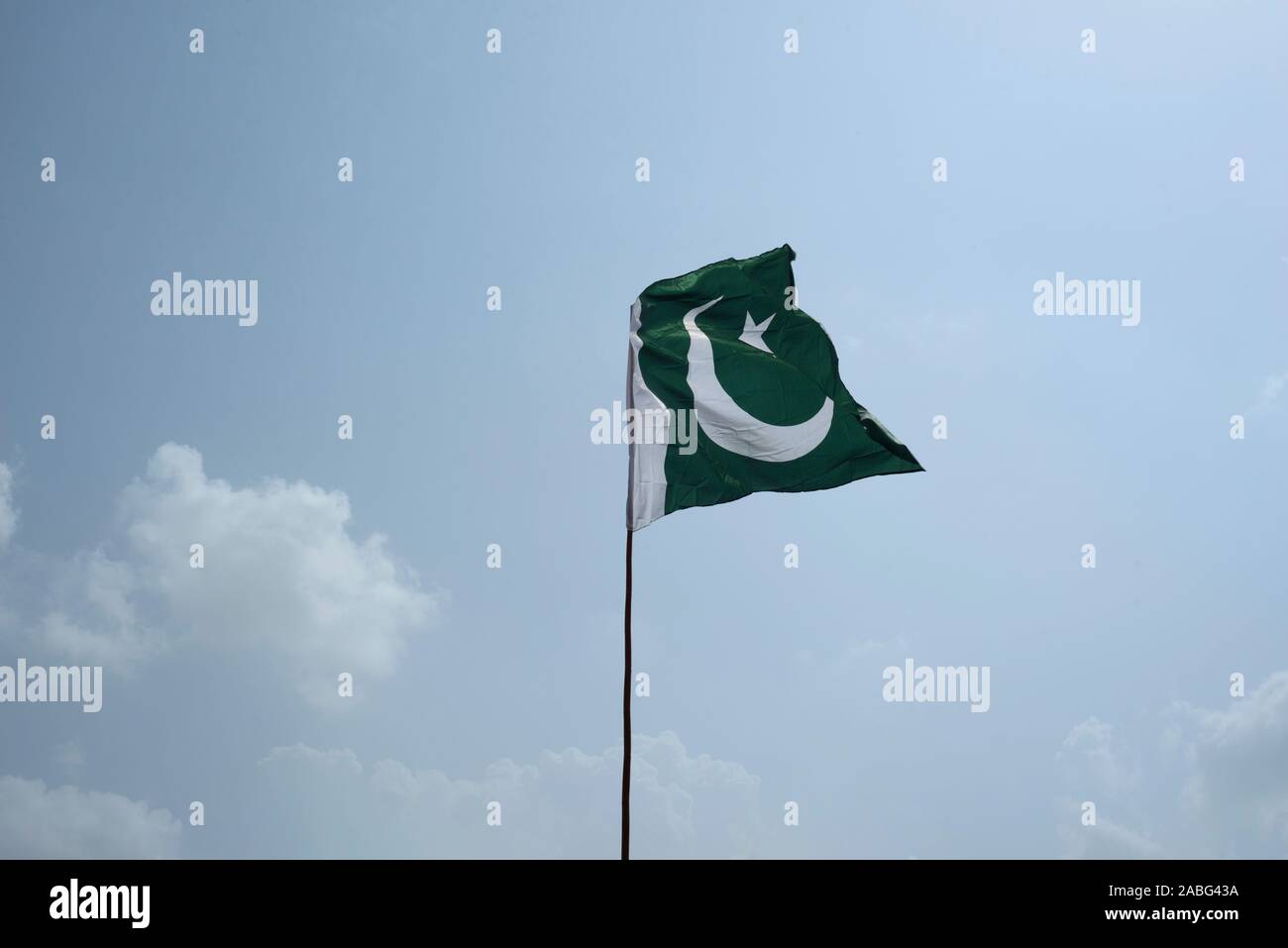 The national flag of Pakistan flying in the blue sky with clouds Stock Photo
