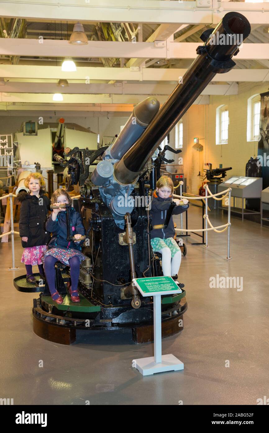 Young children allowed to examine the 4-inch naval Submarine Gun Mk XXIII Mark 23 on display at the Explosion Museum of Naval Firepower; the Royal Navy's former armaments depot of Priddy's Hard, Gosport near Portsmouth, UK. (105) Stock Photo