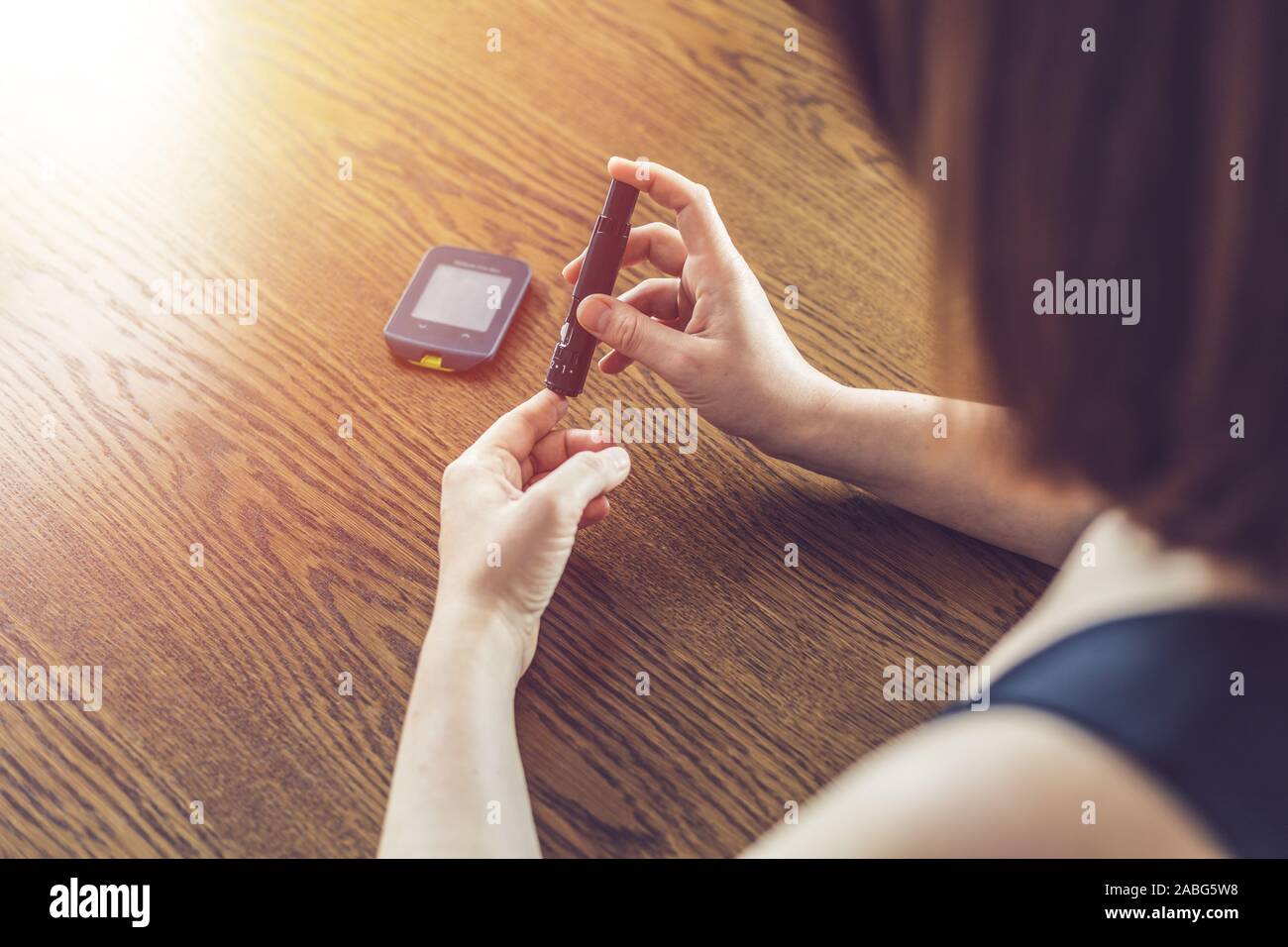 Woman using lancet to take blood sample to check glucose level with traditional glucometer Stock Photo