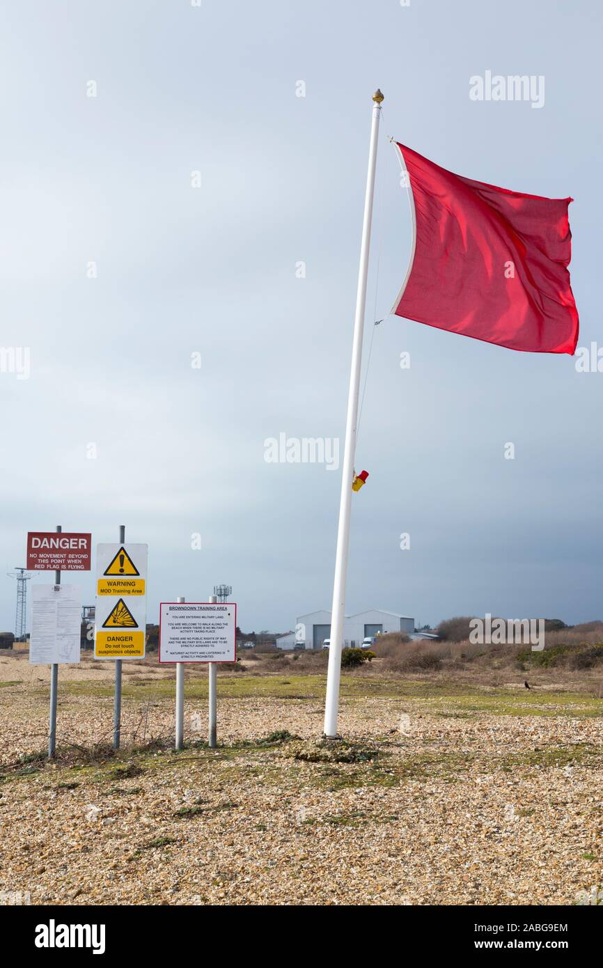 Red flag flying indicating danger and keep out ( MOD estate land area ) with signs / sign & notices at Browndown military training camp coast / coastal base / site / zone. Warning indicates live fire on the live firing range. Lee on the Solent near Gosport and Portsmouth. UK England (105) Stock Photo