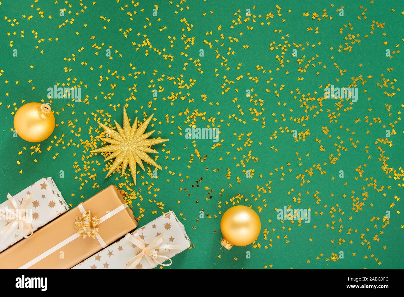 Bright gold star and gift boxes and christmas balls on a green ...