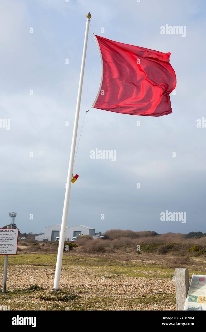 Red flag flying indicating danger and keep out ( MOD estate land area ) with signs / sign & notices at Browndown military training camp coast / coastal base / site / zone. Warning indicates live fire on the live firing range. Lee on the Solent near Gosport and Portsmouth. UK (105) Stock Photo