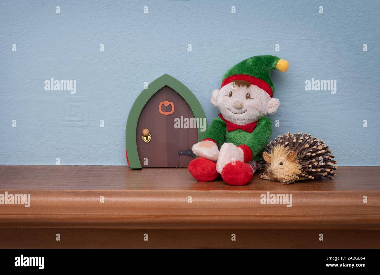Christmas elf sitting next to elf door with toy hedgehog. Cute tradition of sending Santa's elf to check up on children just before christmas. Stock Photo