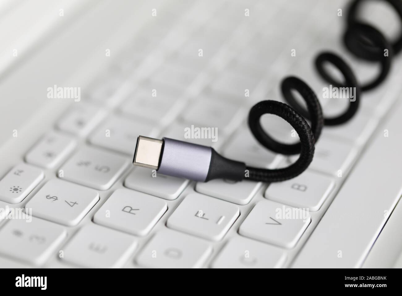 Usb type c cable against laptop keyboard background. Stock Photo