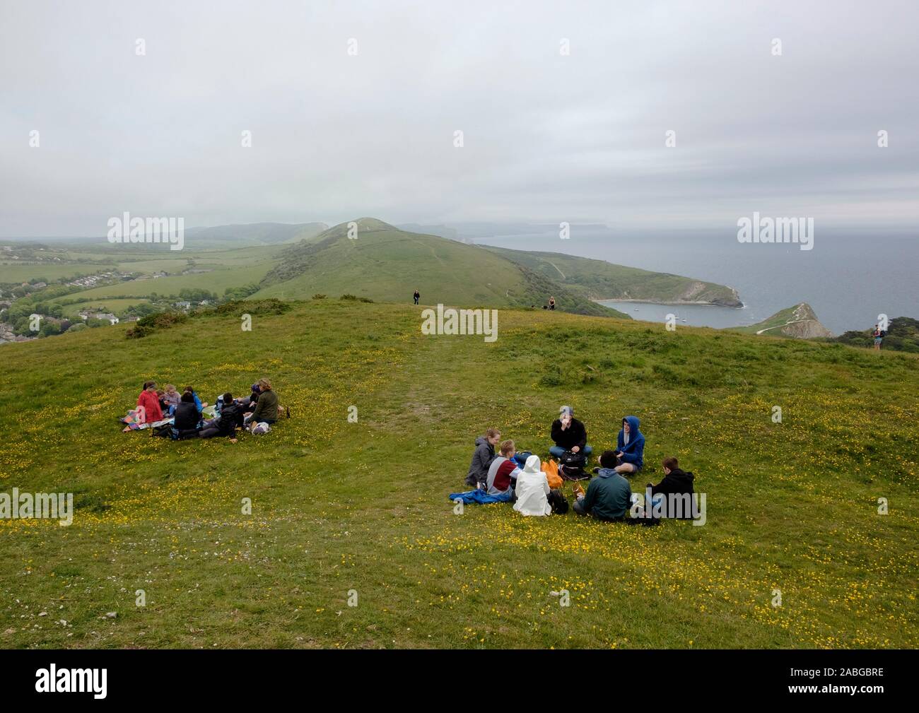 Two groups picnicing on Hanbury Tout with views to Lulworth Cove and of the Purbeck Hills Stock Photo