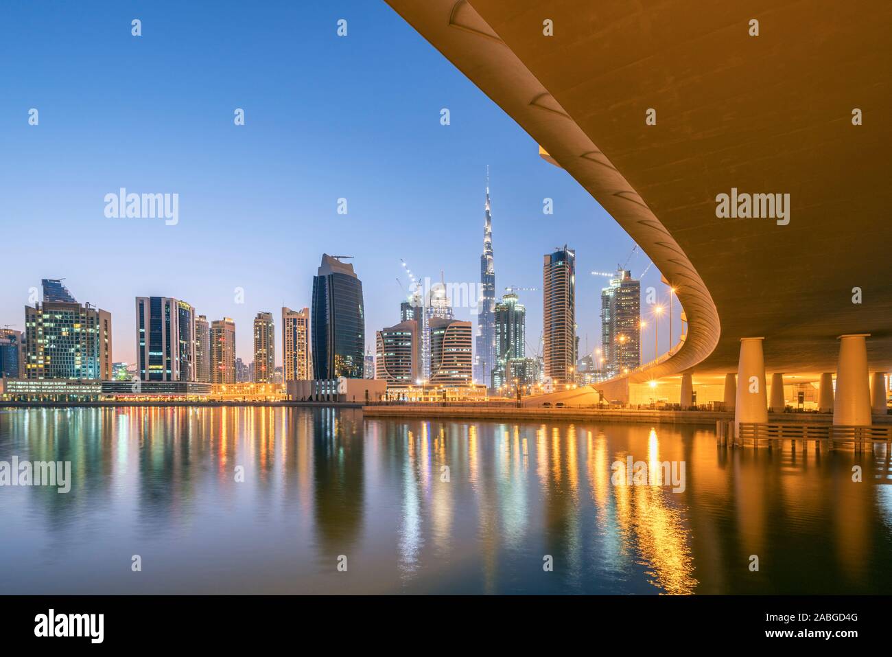 Skyline of towers at dusk in Business Bay next to bridge across the Creek in Dubai United Arab Emirates Stock Photo