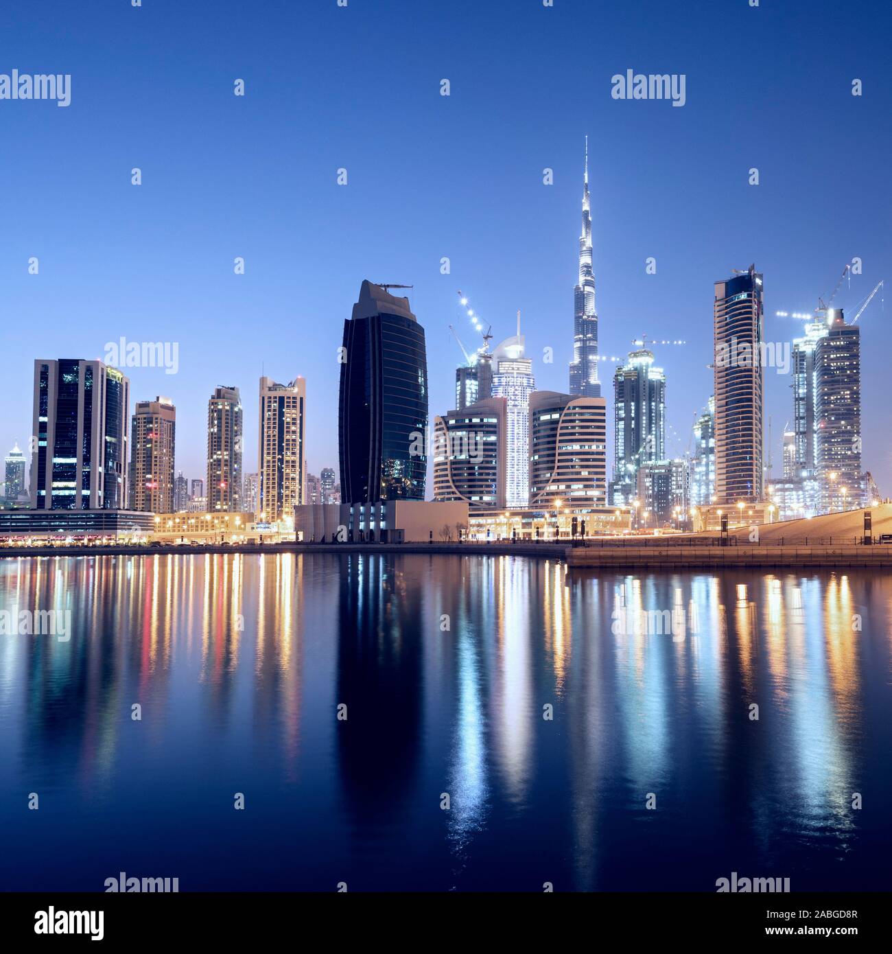 Skyline of towers reflected in the Creek at dusk in Business Bay  in Dubai United Arab Emirates Stock Photo