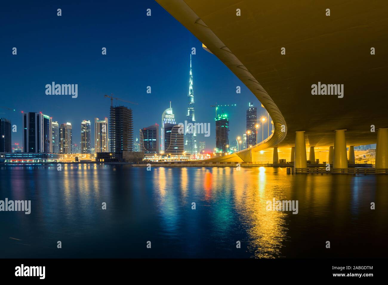 Night view of skyline of new Business Bay District towards Burj Khalifa tower  from The Creek river in Dubai United Arab Emirates Stock Photo