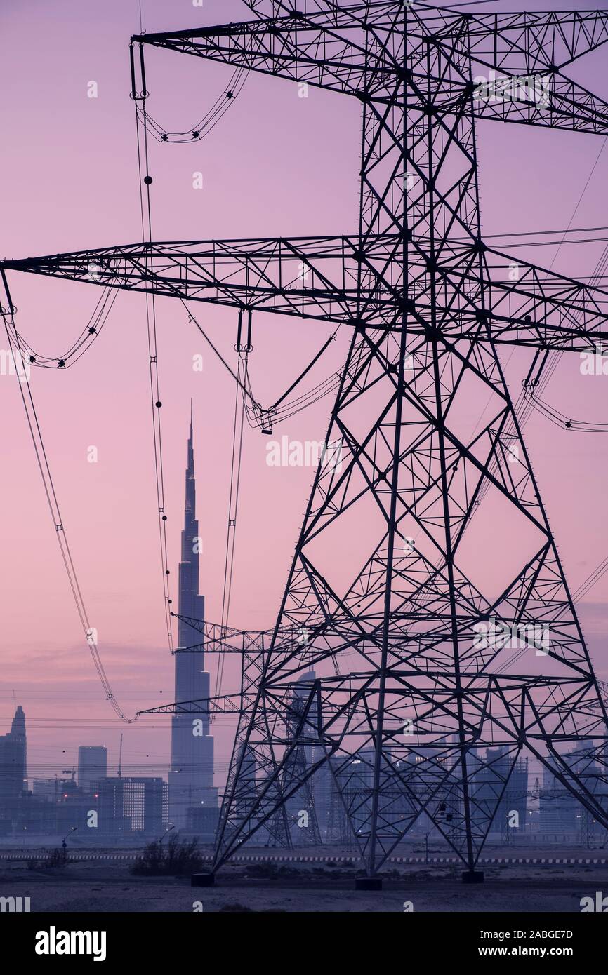 Electricity transmission lines and pylons and skyline  at dusk in Dubai United Arab Emirates Stock Photo