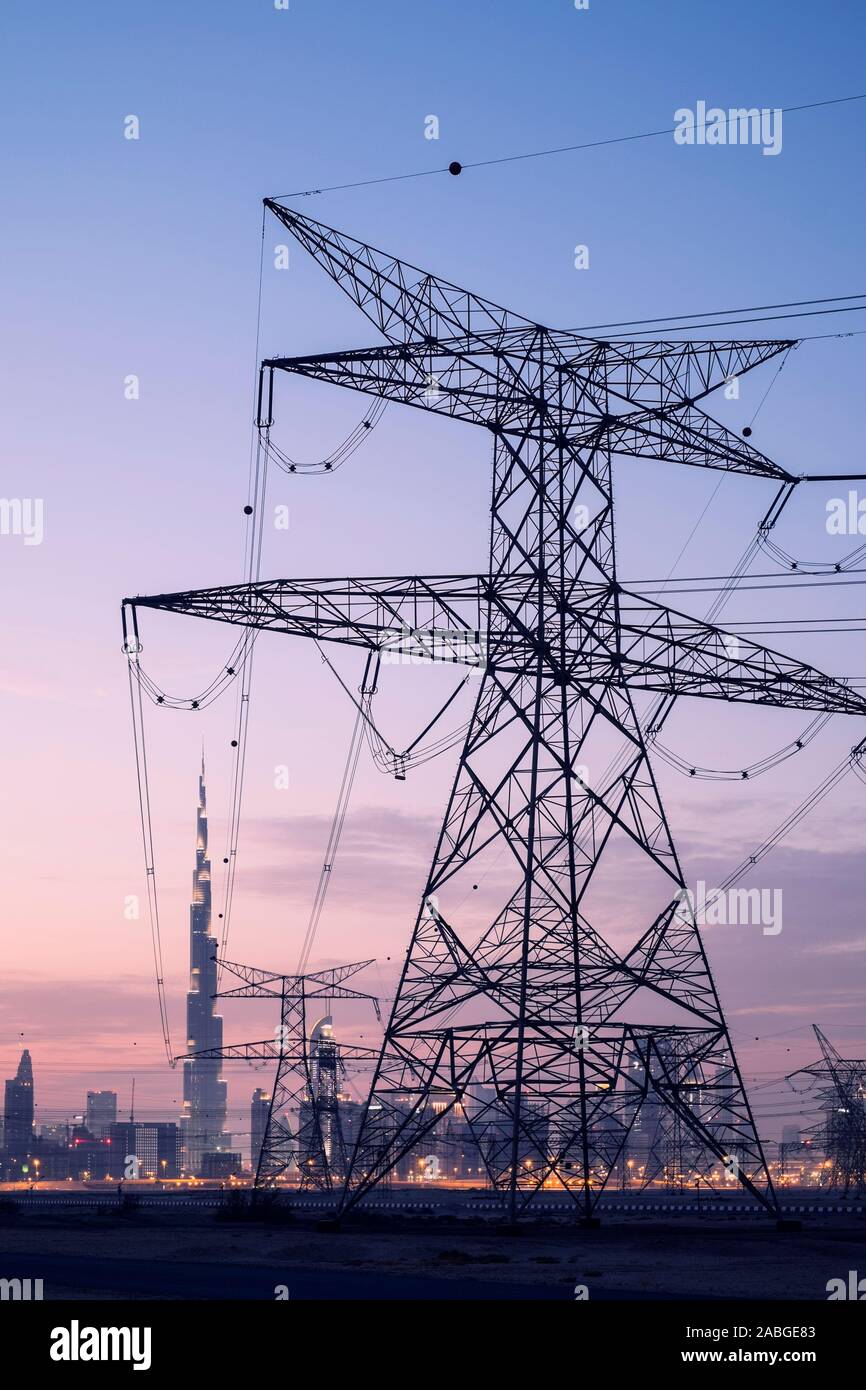 Electricity transmission lines and pylons and skyline  at dusk in Dubai United Arab Emirates Stock Photo