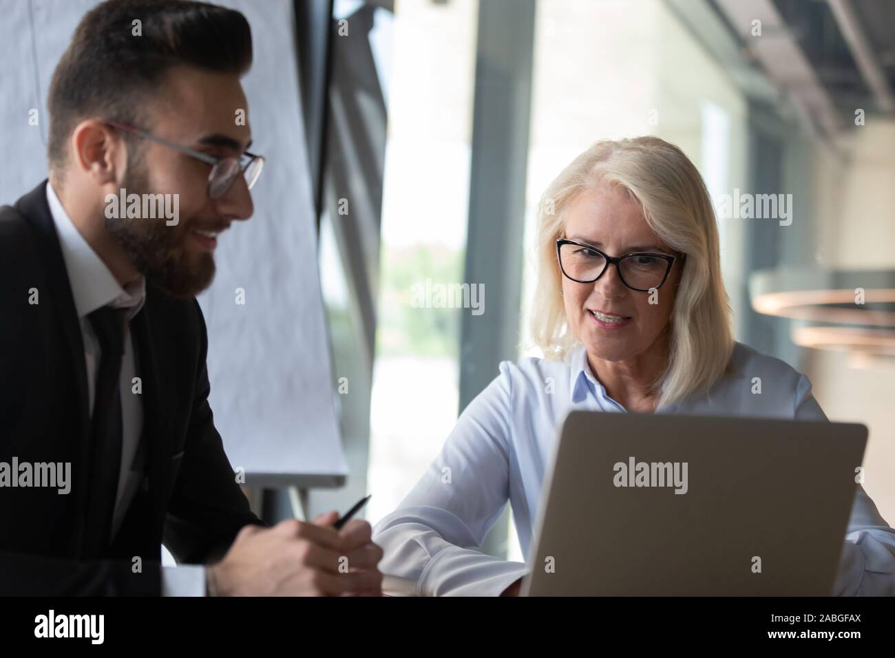 Multiracial businesspeople discuss project at laptop at meeting Stock Photo