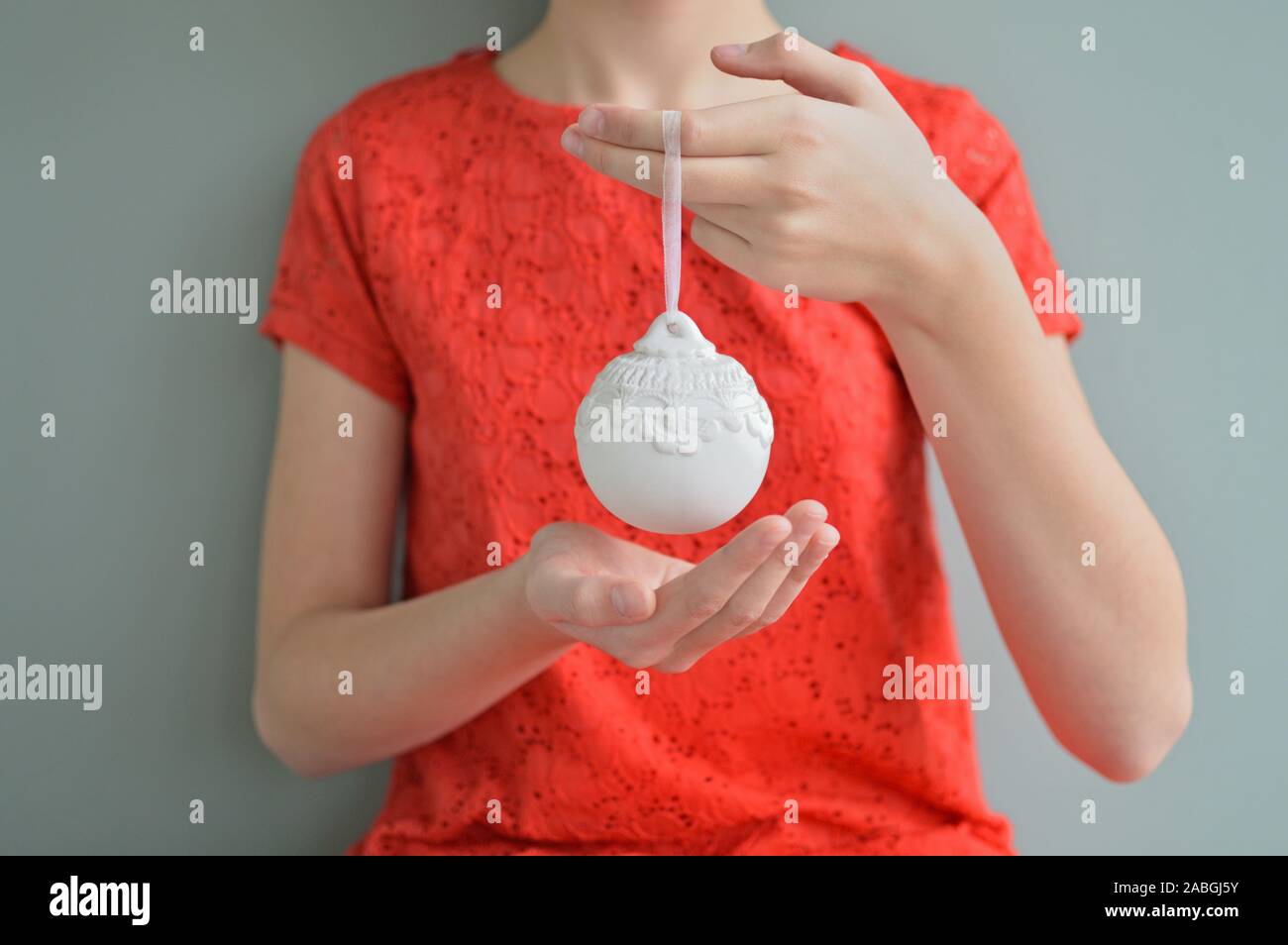 White Christmas decoration held by girl in red dress Stock Photo