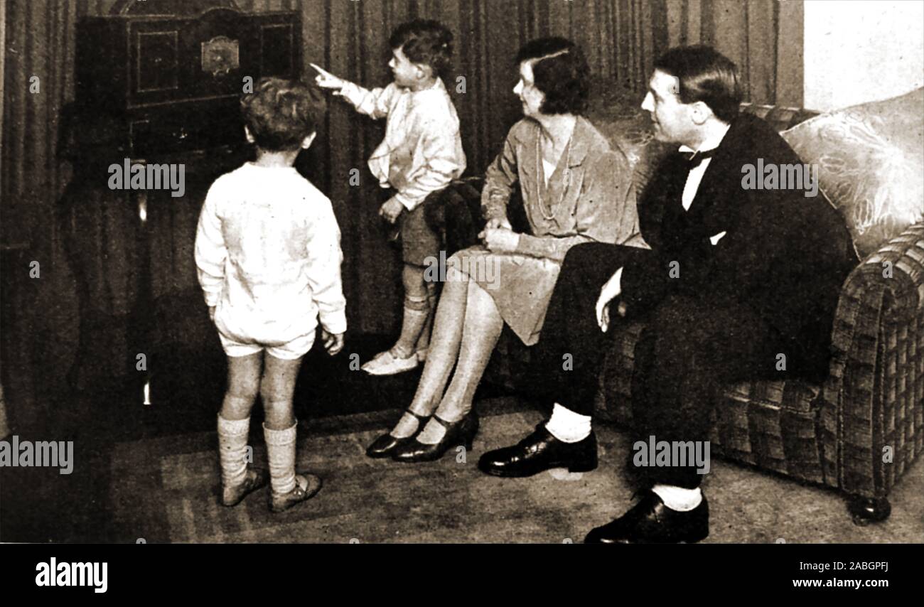 Early television (1920's-30s)  - An unusual photograph of a family group watching an early Baird Televiser.  The home constructed mechanical-scan television receiver produced a picture using a spinning metal ' Nipcow' disk with holes in it,  whilst a lamp   produced a 48 line scan  to initially produce a poor dim orange image 1.5 inches square,  at 7.5 frames per second. Stock Photo