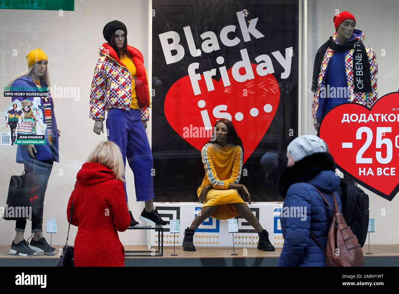 People look at a board with Black Friday sales discounts, outside a store. Black Friday is an informal name for the Friday following Thanksgiving Day in the United States which is celebrated on the fourth Thursday of November. The Black Friday is a sales offer to attract shoppers for the Christmas shopping season. Stock Photo