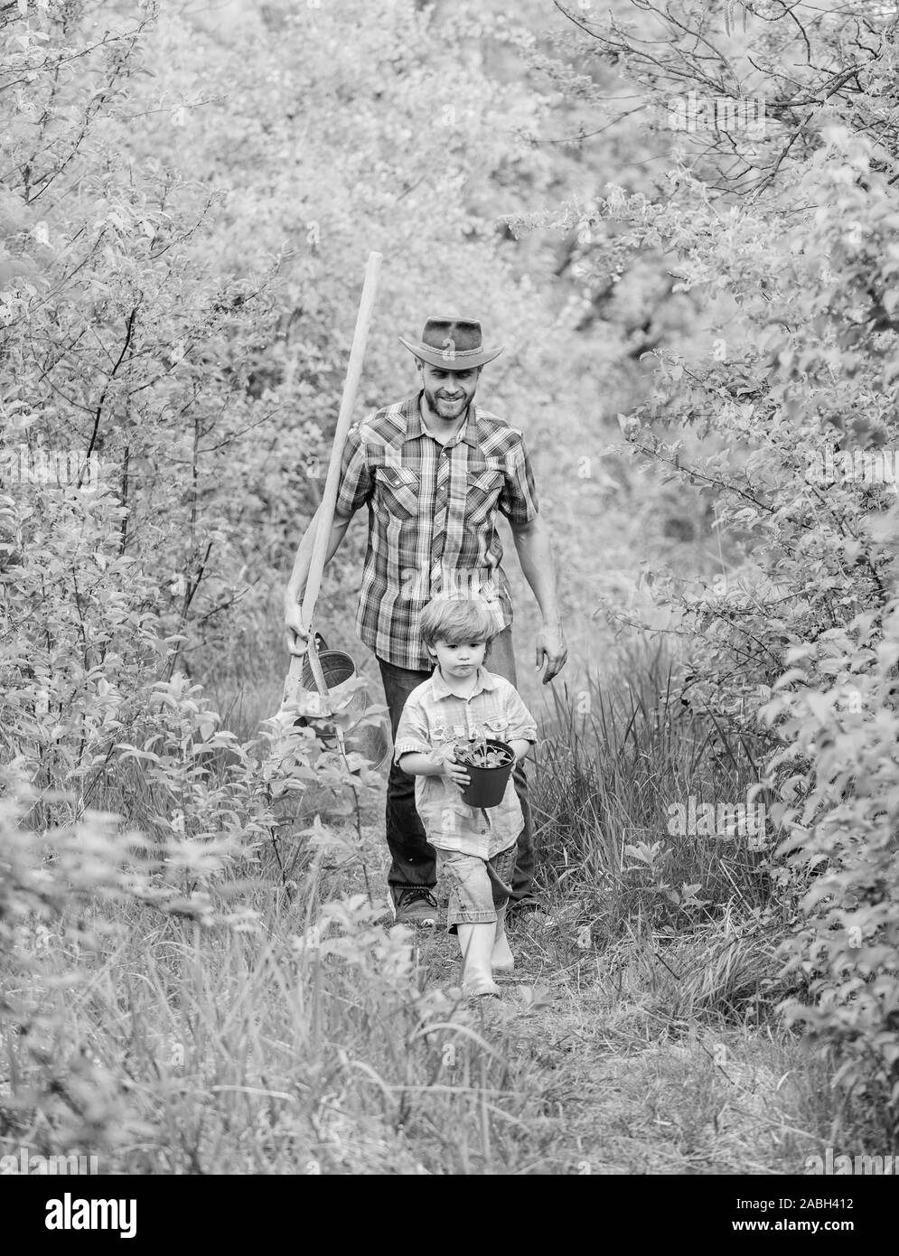 Little helper in garden. Planting flowers. Growing plants. Boy and father in nature with watering can and shovel. Dad teaching son care plants. Arbor day. Planting trees. Tree planting tradition. Stock Photo