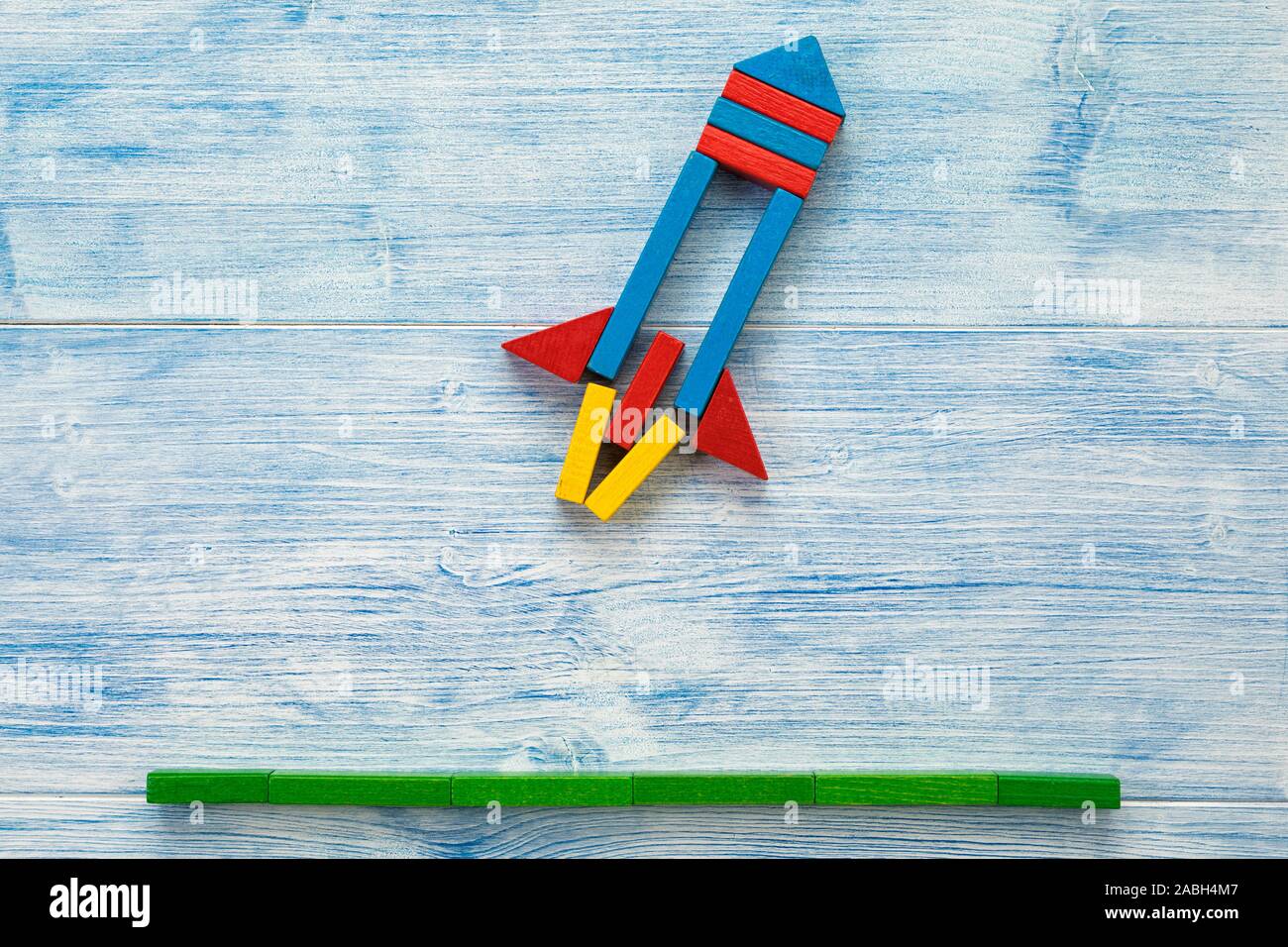 Startup concept, rocket from building blocks on wood background lift off flat lay Stock Photo