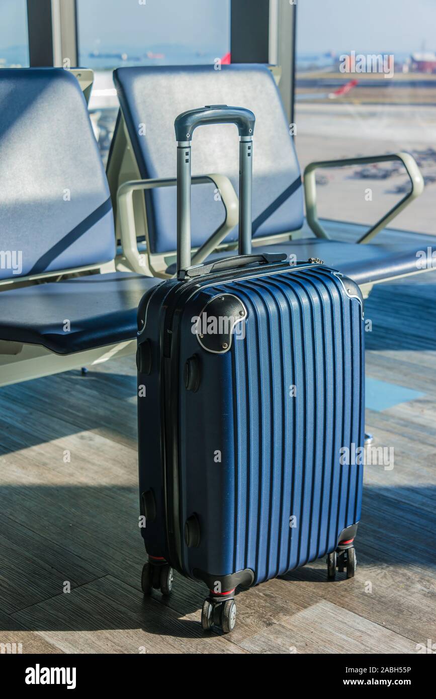 Small plastic travel suitcase in the airport hall. Stock Photo