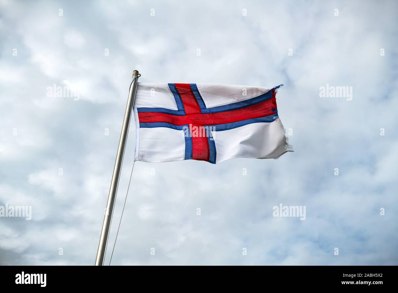 Flag of Faroe islands waving against a cloudy sky Stock Photo