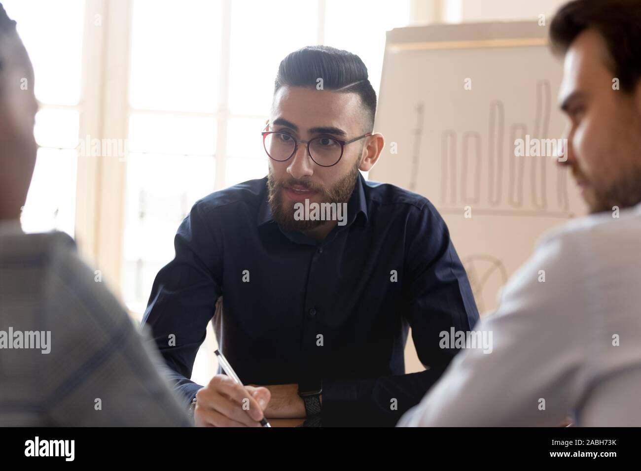 Middle eastern ethnicity young businessman listening to multiracial partners. Stock Photo