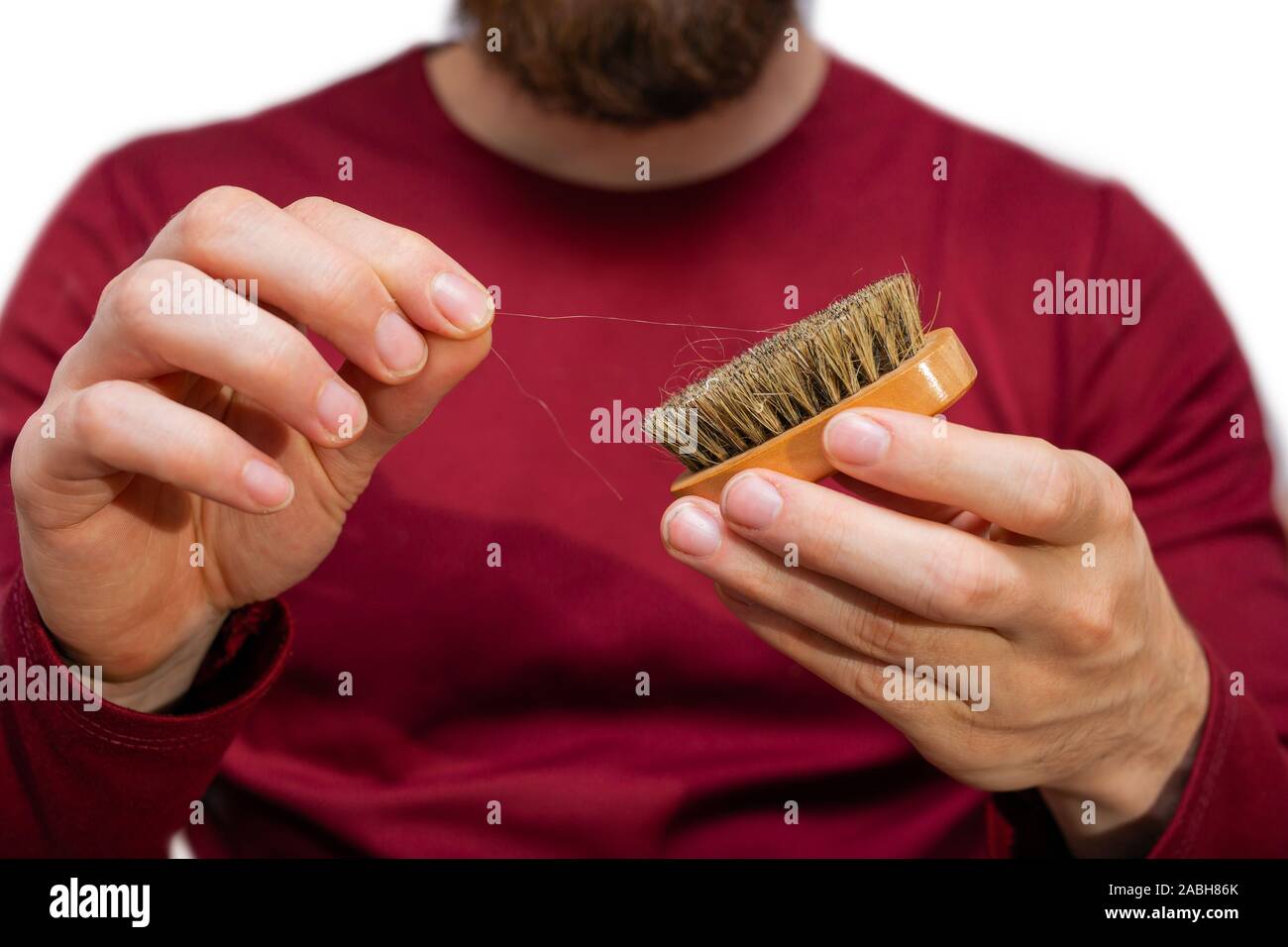 Man with beard pulls hair out beard brush, close-up of cleaning hair isolated on white Stock Photo