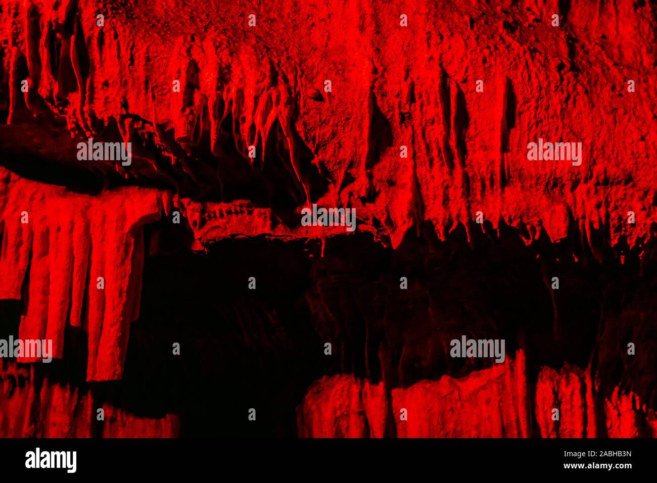 Illuminated with red light Cave with stalactites background Stock Photo