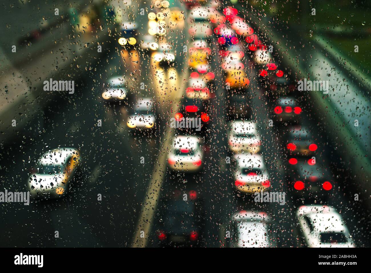 Urban background with blurry cars and expensive, shallow depth of field. Rainy and cloudy day. Car traffic shot through glass, focusing on raindrops Stock Photo