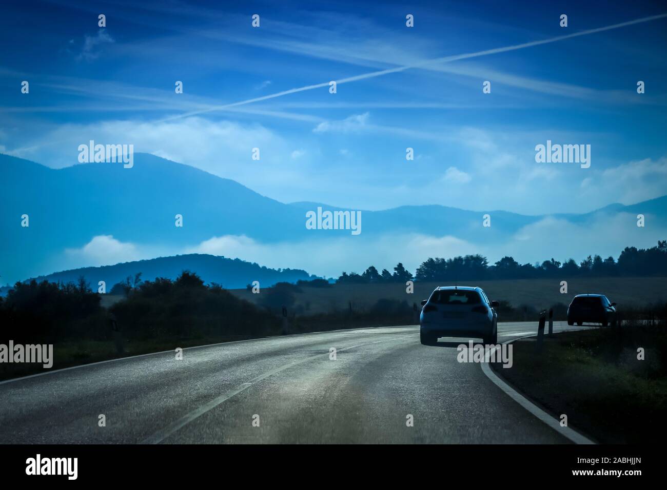 Rear view of two cars driving on the two way road with landscape of ...