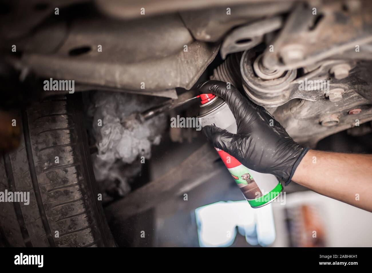Car master mechanic repairer lubricates the screws with a machine parts cleaner oil dirt grease