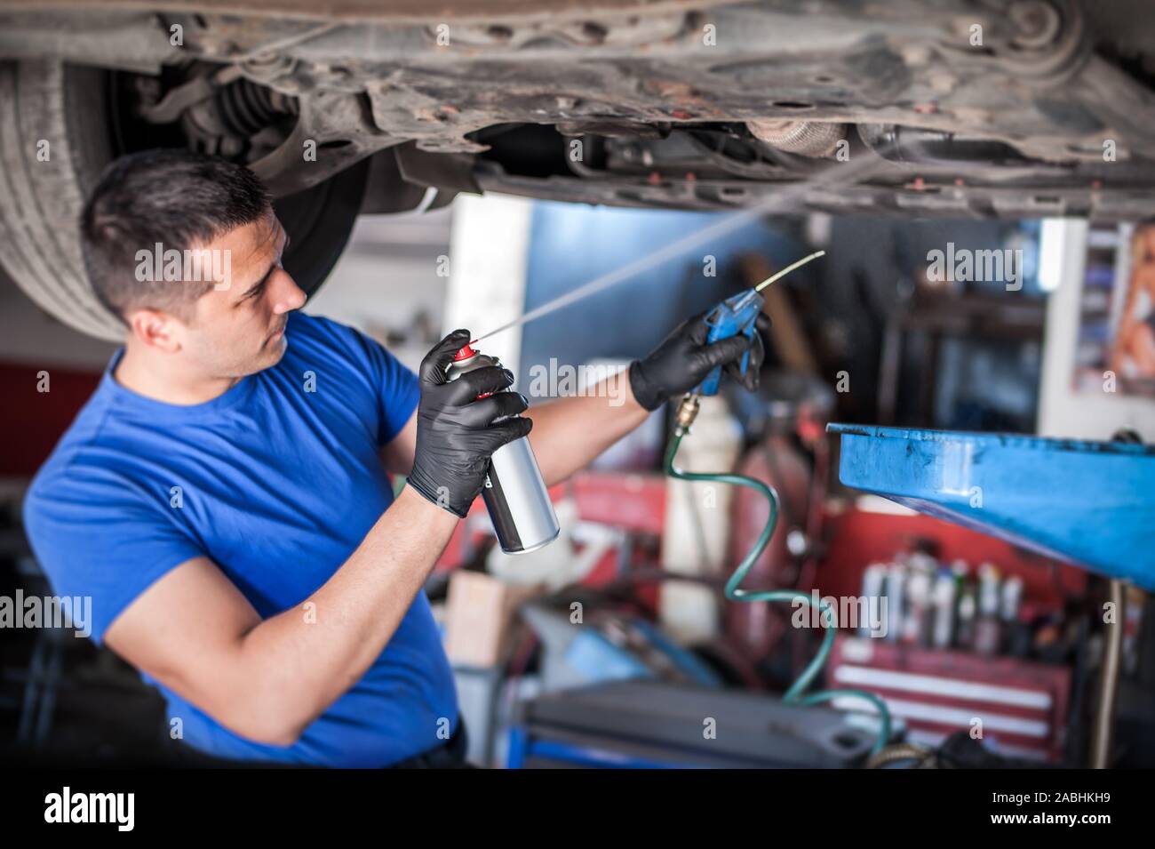 Car master mechanic repairer lubricates the screws with a machine parts cleaner oil dirt grease