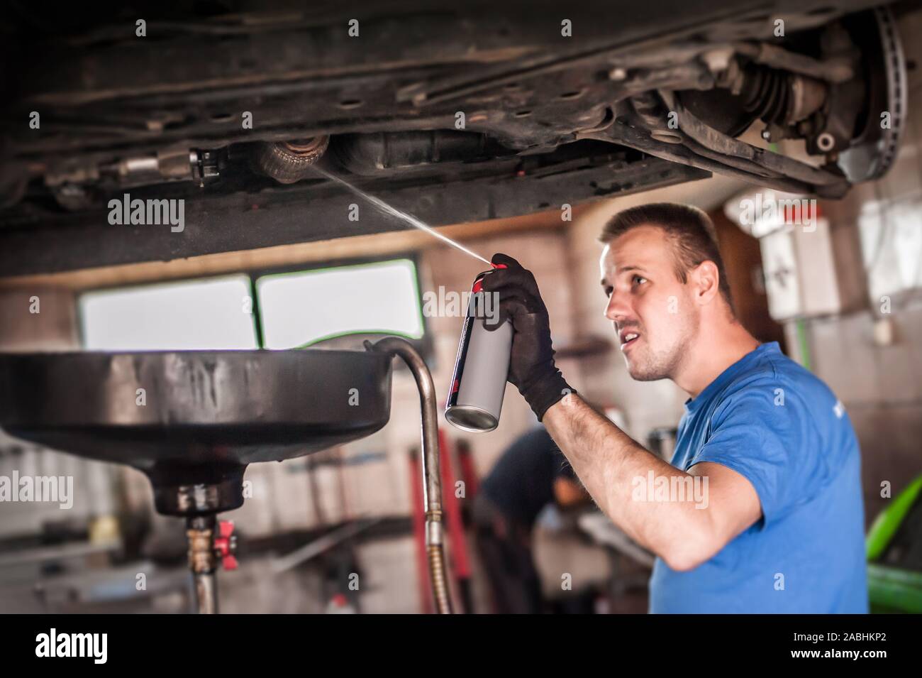 Car master mechanic repairer lubricates the screws with a machine parts cleaner oil dirt grease