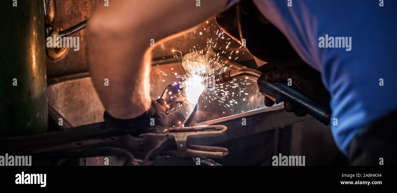 Auto mechanic working with welding mask cooking metal on automatic welding  machine for repairing cardan shafts in service workshop. Sparks flying in t  Stock Photo - Alamy