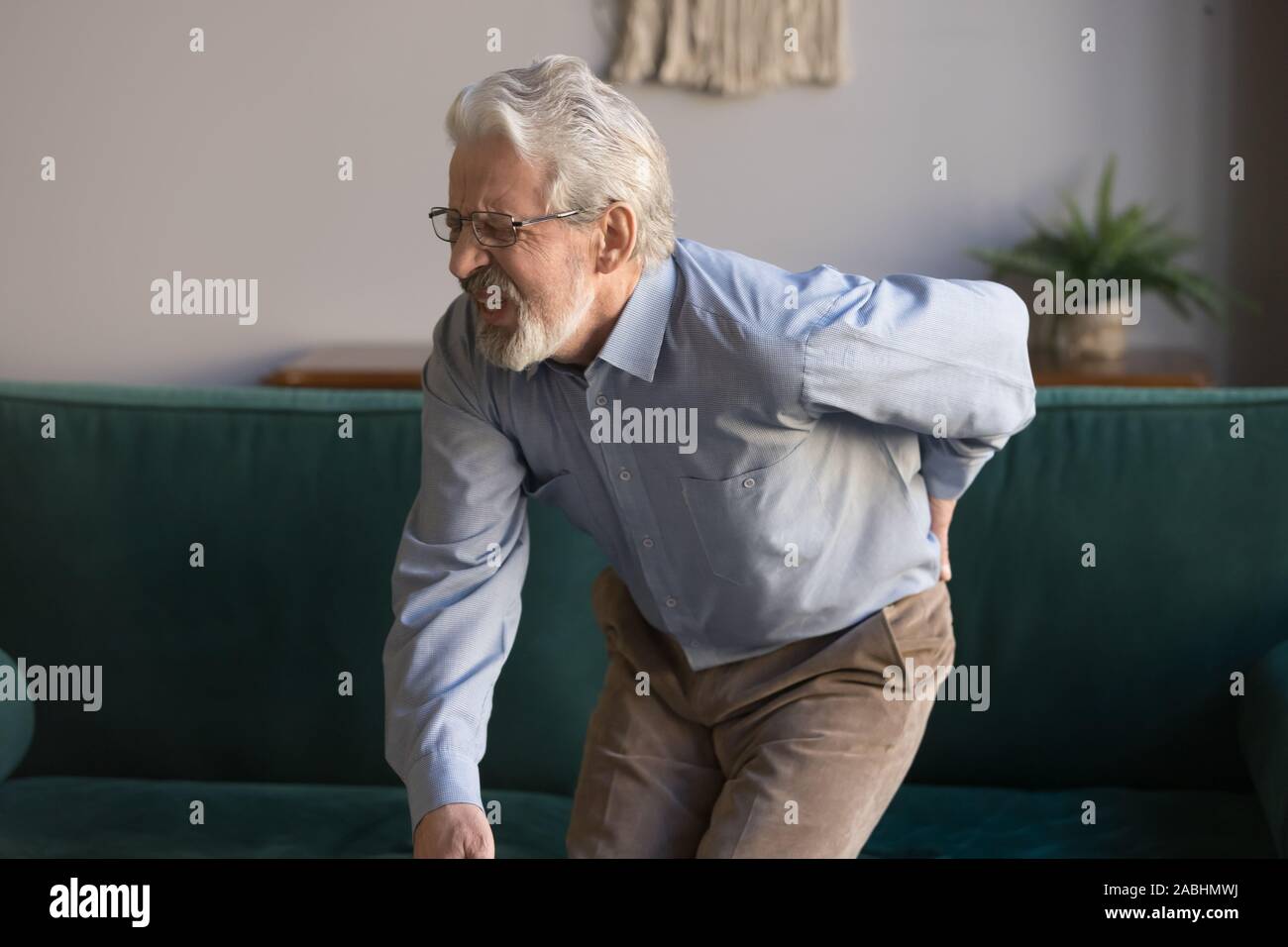 Elderly man writhes in pain suffers from low back strain Stock Photo