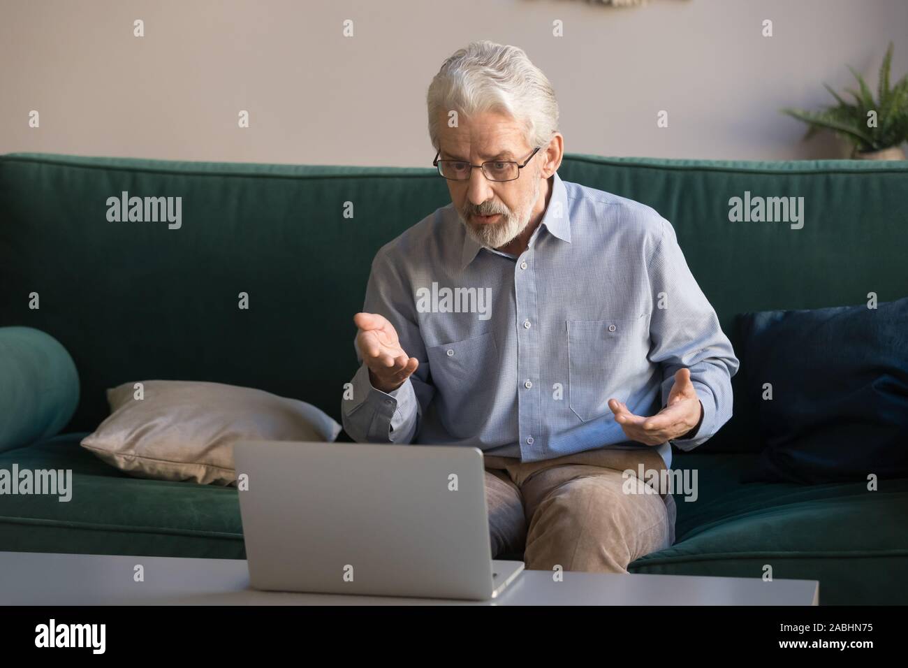 Elderly man makes video call talking looking at computer screen Stock